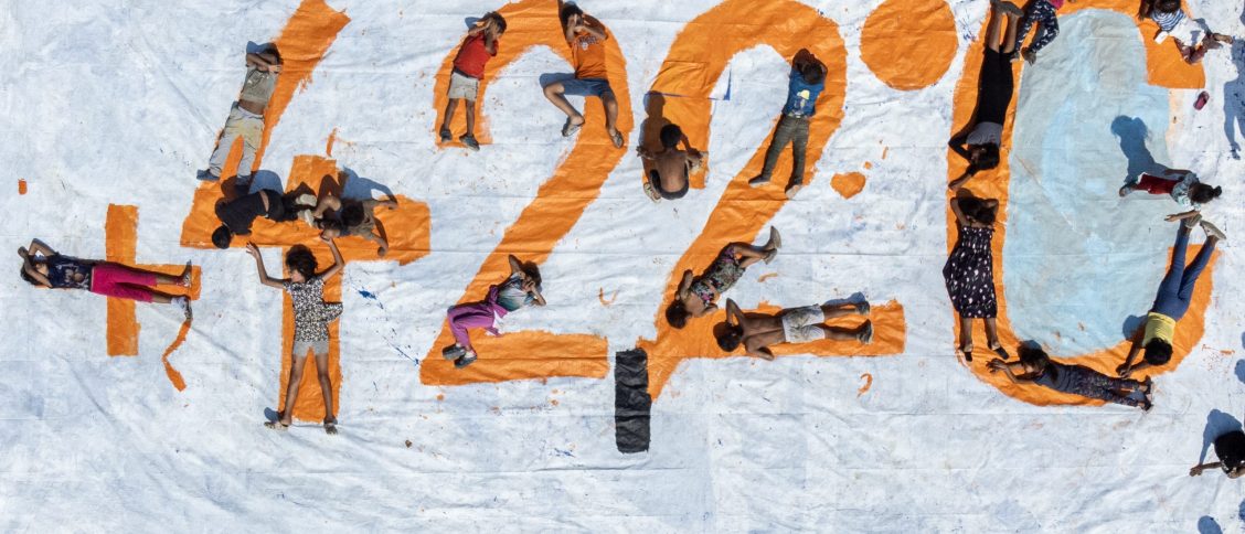 Deti ležiace na oranžovom nápise „42,2 °C“ namaľovanom na veľkom plátne.